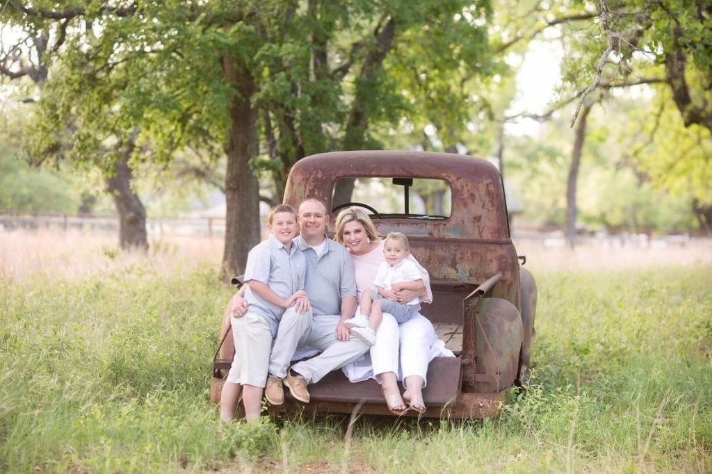 family sitting on the back of a truck